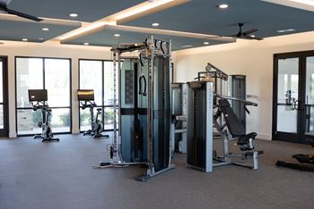 A gym with a variety of equipment including a squat rack, a leg press machine, and a bench press.
